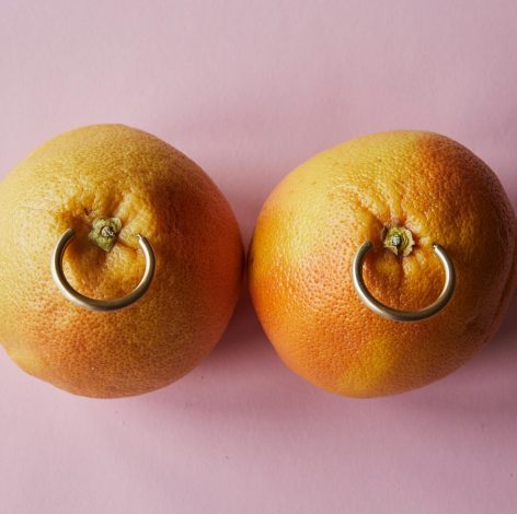 Whimsical grapefruits with shiny rings on a soft pink background, blending nature and creativity.