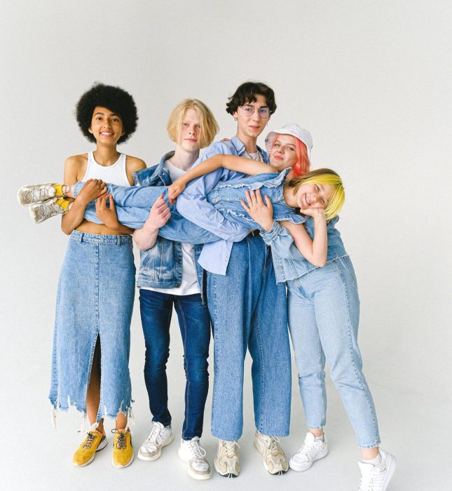 Cheerful friends in trendy denim celebrate friendship against a bright white background.