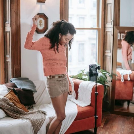Joyful woman dancing in a cozy, brightly lit living room with vibrant decor.