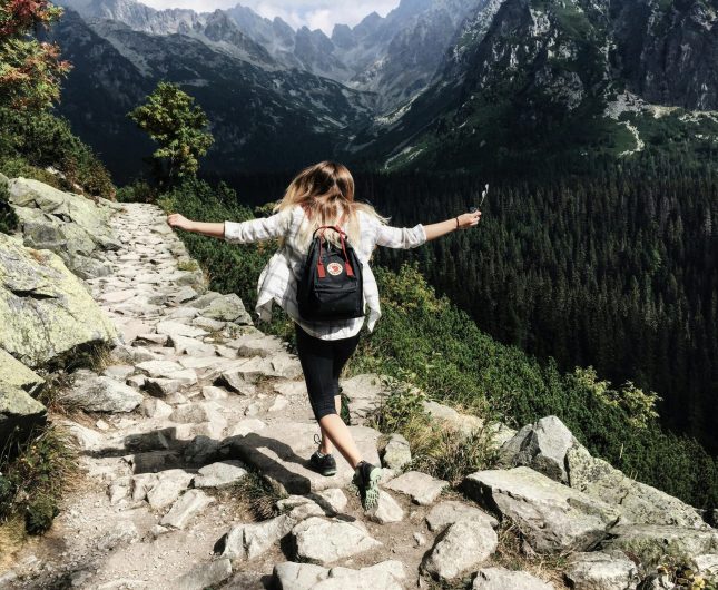 Happy hiker enjoying a sunny mountain trail surrounded by stunning natural beauty.
