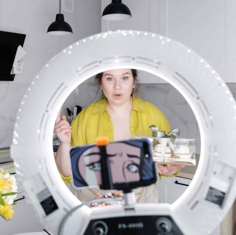 Young woman in yellow top creates engaging recipe content in a bright, modern kitchen.
