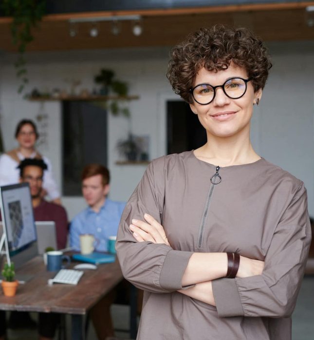 Confident woman in modern office fosters collaboration among colleagues in a vibrant workspace.