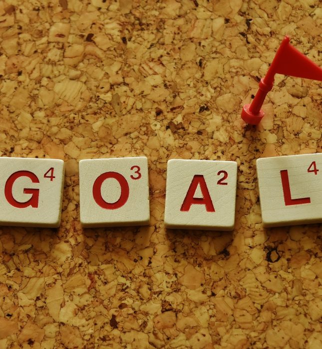 Bold red GOAL tiles on corkboard symbolize clarity and success in achieving your dreams.