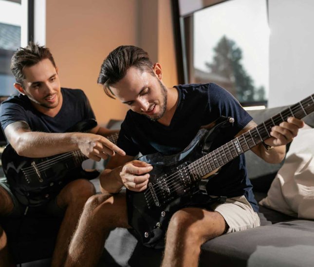 Man teaching friend to play electric guitar