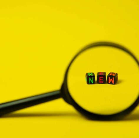 Explore new possibilities with a magnifying glass highlighting colorful blocks spelling NEW.