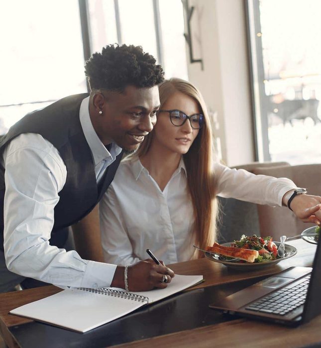 Modern workspace collaboration with food, notebook, and enthusiastic professionals sharing ideas.