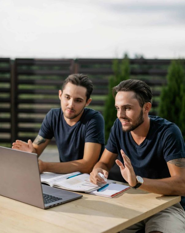 Two men studying together with a laptop outdoors
