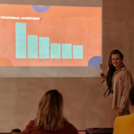 Young woman presents engaging data to attentive audience in a warm, modern learning space.