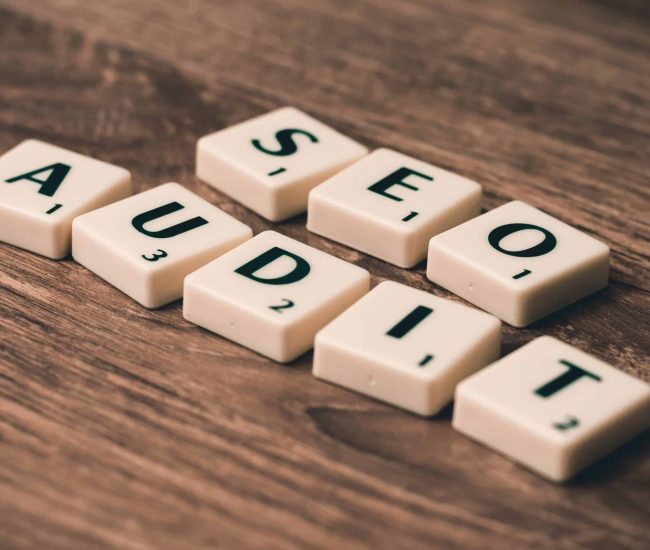Letter tiles spelling SEO AUDIT on a rustic wooden background, highlighting digital marketing importance.
