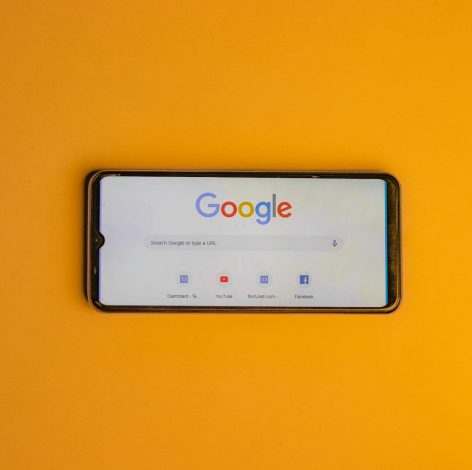 Sleek smartphone displaying Google search on a vibrant yellow background for digital connectivity.