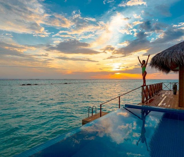 Joyful sunset celebration by the infinity pool and tranquil ocean in a tropical paradise.