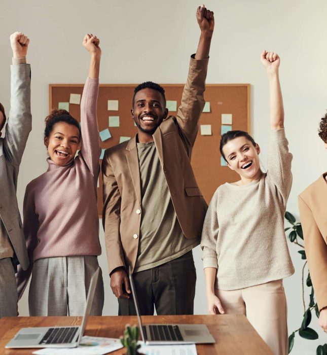 Diverse team celebrates project success in a bright, modern office with collaboration and camaraderie.