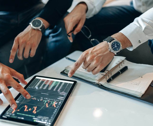 Team collaboration analyzing digital business data with graphs and handwritten notes.