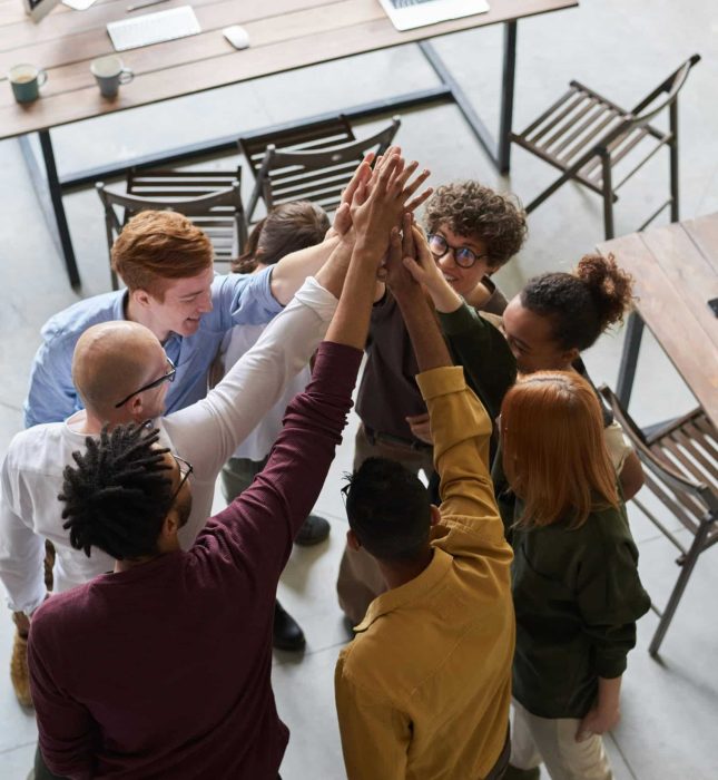 Diverse team celebrating success with high-fives in a modern, collaborative office environment.