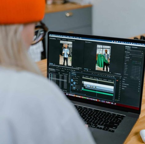 Video editor in a cozy workspace, focused on editing clips on a laptop.