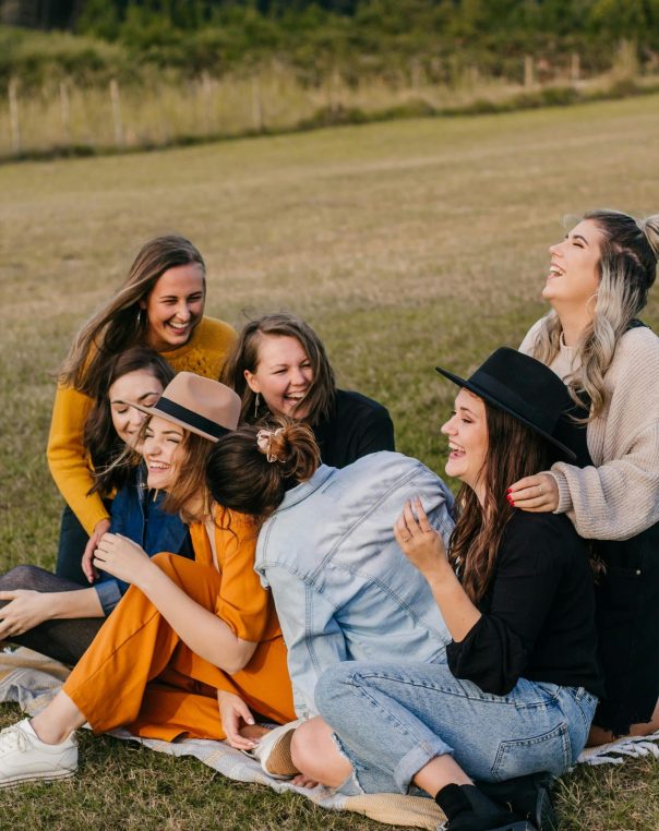 Seven women enjoy laughter and friendship in a beautiful, natural outdoor setting.