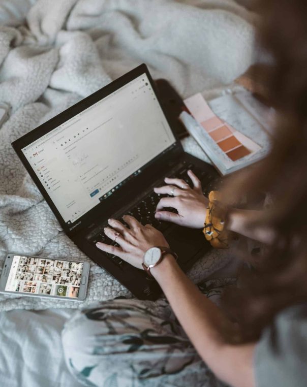 Cozy workspace: individual typing on a laptop with color palette and smartphone nearby.