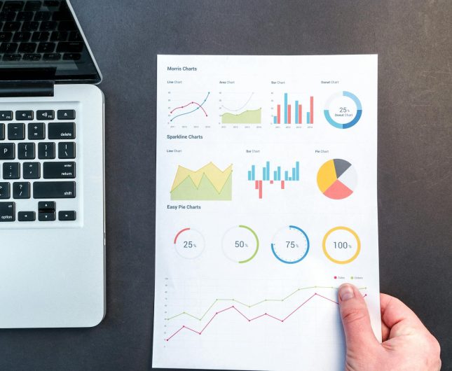 Sleek laptop on dark desk with colorful data visualization graphs for performance analysis.