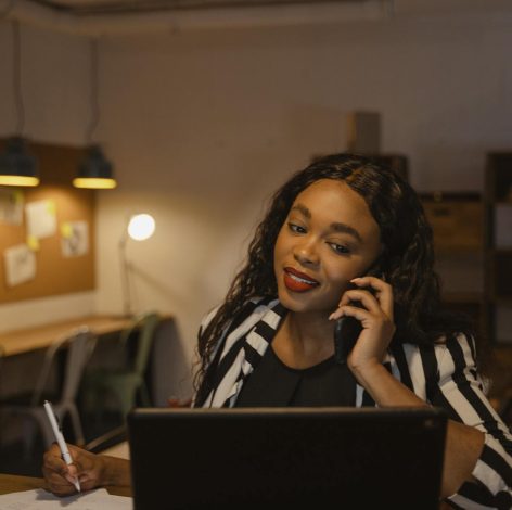 Young professional multitasking in a modern co-working space with tablet and phone.