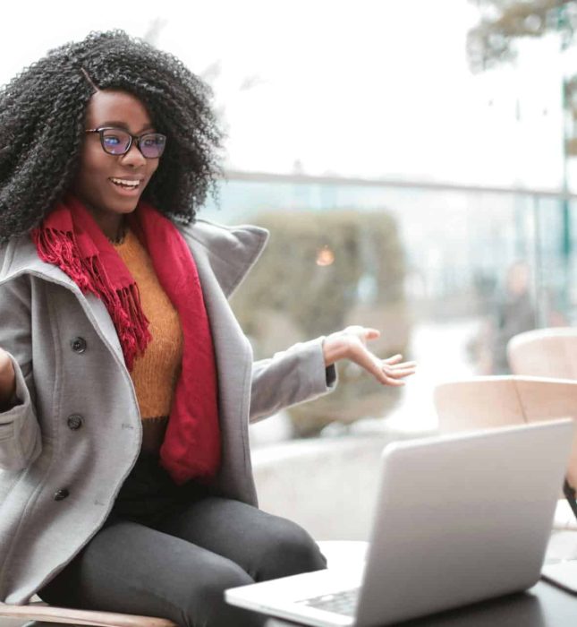 Stylish woman with glasses enjoys lively conversation at an outdoor cafÃ© in autumn.
