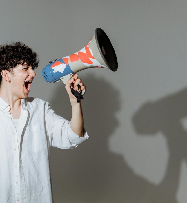 Young person passionately amplifying their message with a colorful megaphone against a muted background.